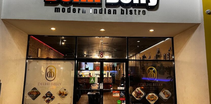Top Vegetarian Indian Dishes in Alhambra 4 Front entrance of Delhi Belly – Modern Indian Bistro in Alhambra, featuring illuminated signage and inviting glass windows showcasing vibrant food images.