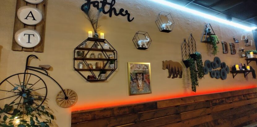 How Delhi Belly brings Indian Flavors into their dishes 3 Indian restaurant cozy dining wall decor featuring rustic shelves, vintage bicycle art, plants, and "Gather" and "Eat" signs.